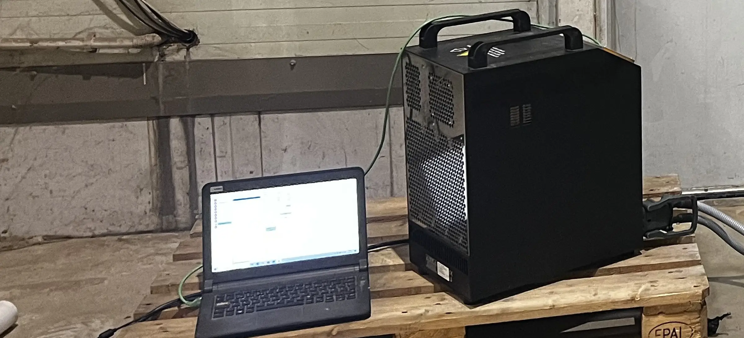 Urządzenie do regeneracji i laptop na palecie obok wózka wysokiego składowania w hali klienta